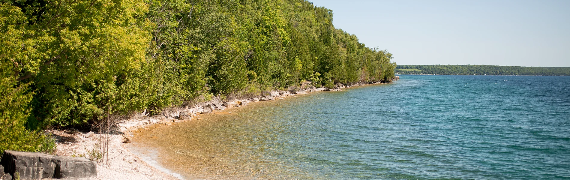 A rocky shoreline on a tree lined lake